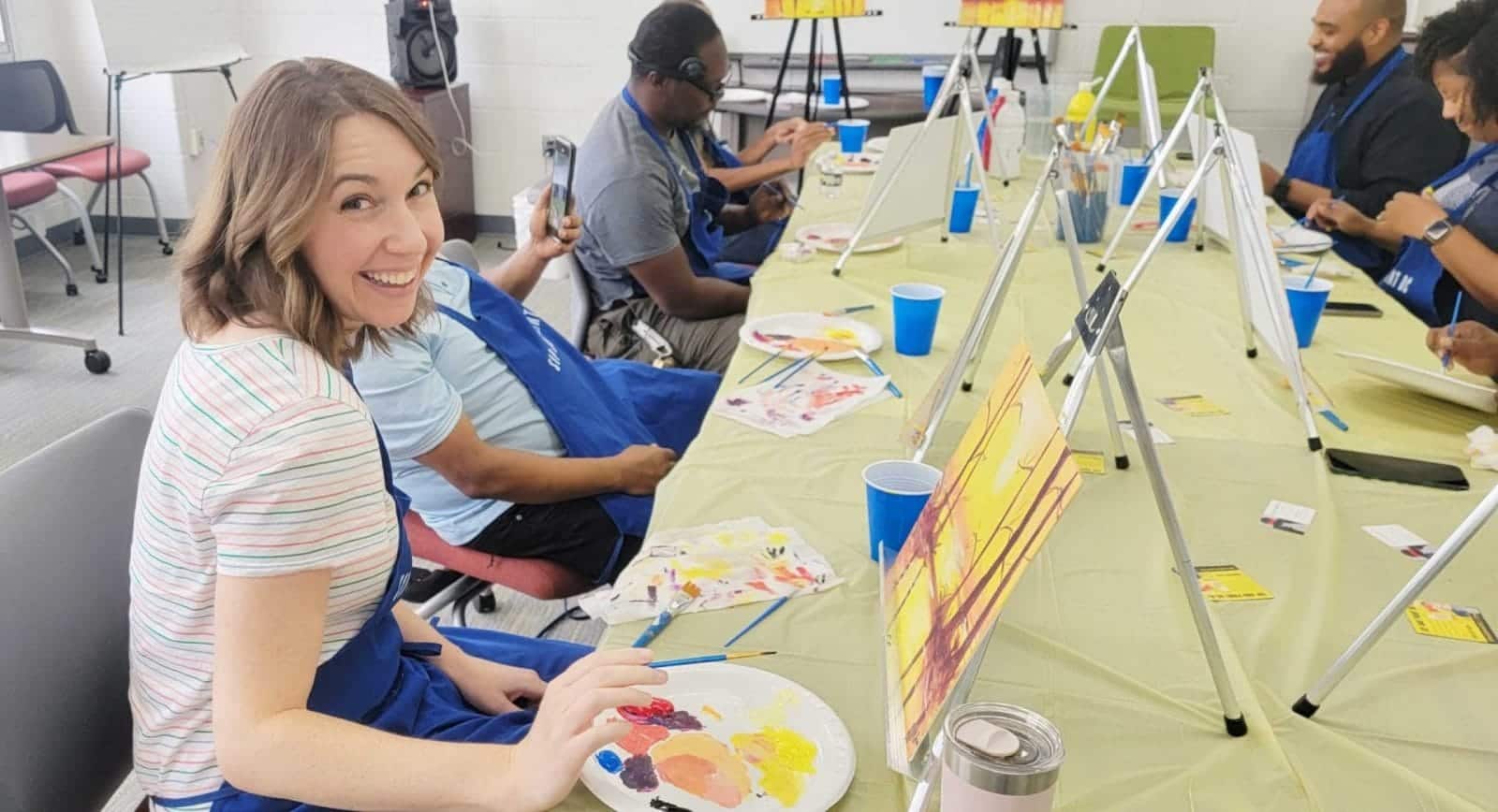 A group of people enjoying a paint and sip session at a table.