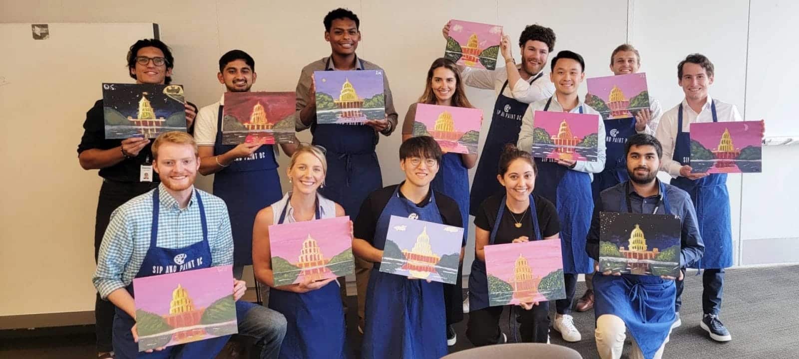 A group of people attending a DC Paint and Sip event, showcasing their painting in an office setting