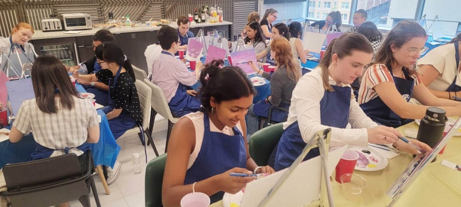 A best group near me having a paint and sip at a table in a classroom in DC.