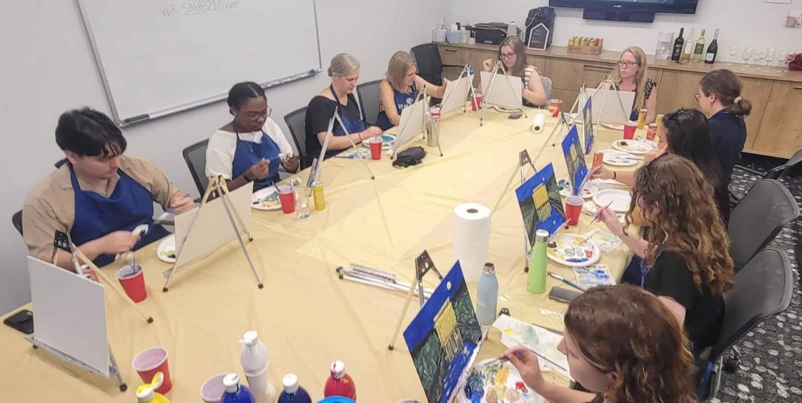 A group of people enjoying a dc sip and paint session at a restaurant table.