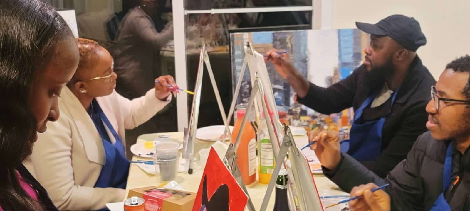 A paint and sip experience in Washington DC where a group of people gather to create art on easels.